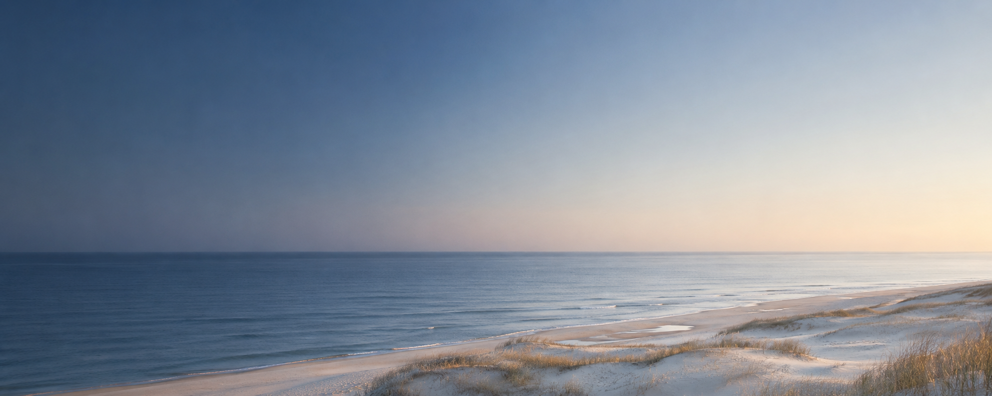 Sand dunes and open blue ocean at dawn